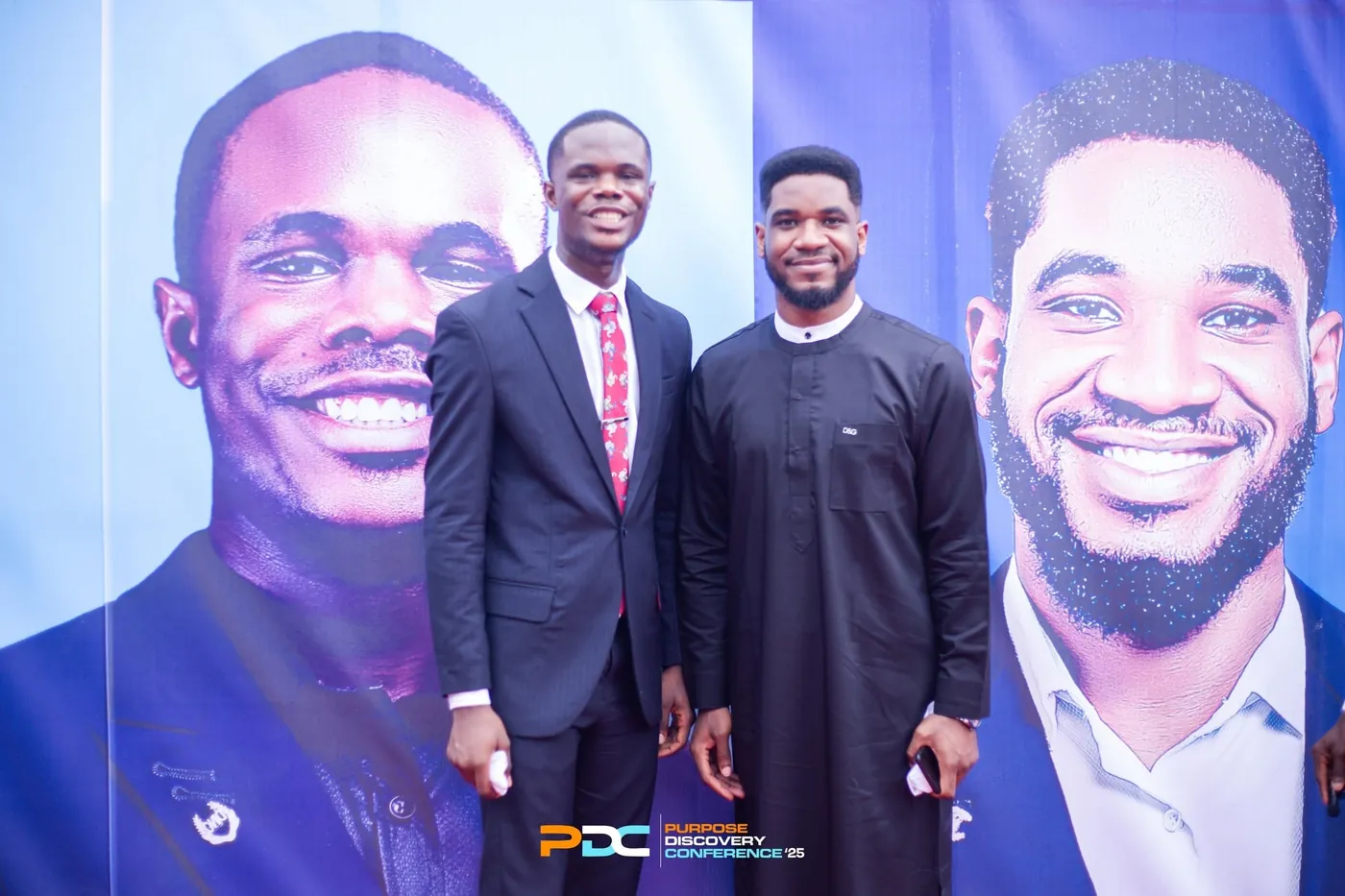 Paul Udah with a guest beside the conference banners